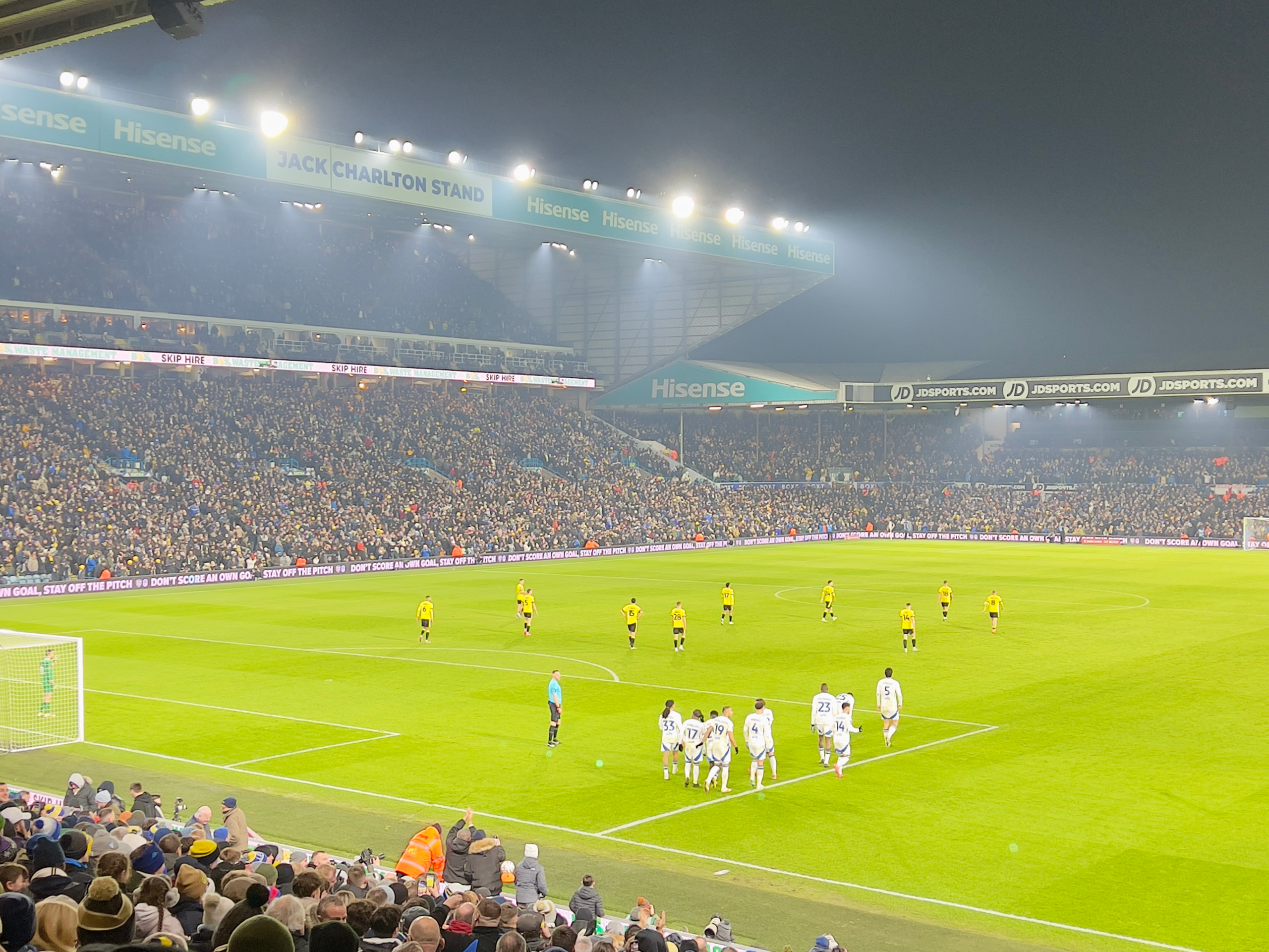 Packed stands at Elland Road with Leeds United supporters. Players on pitch.