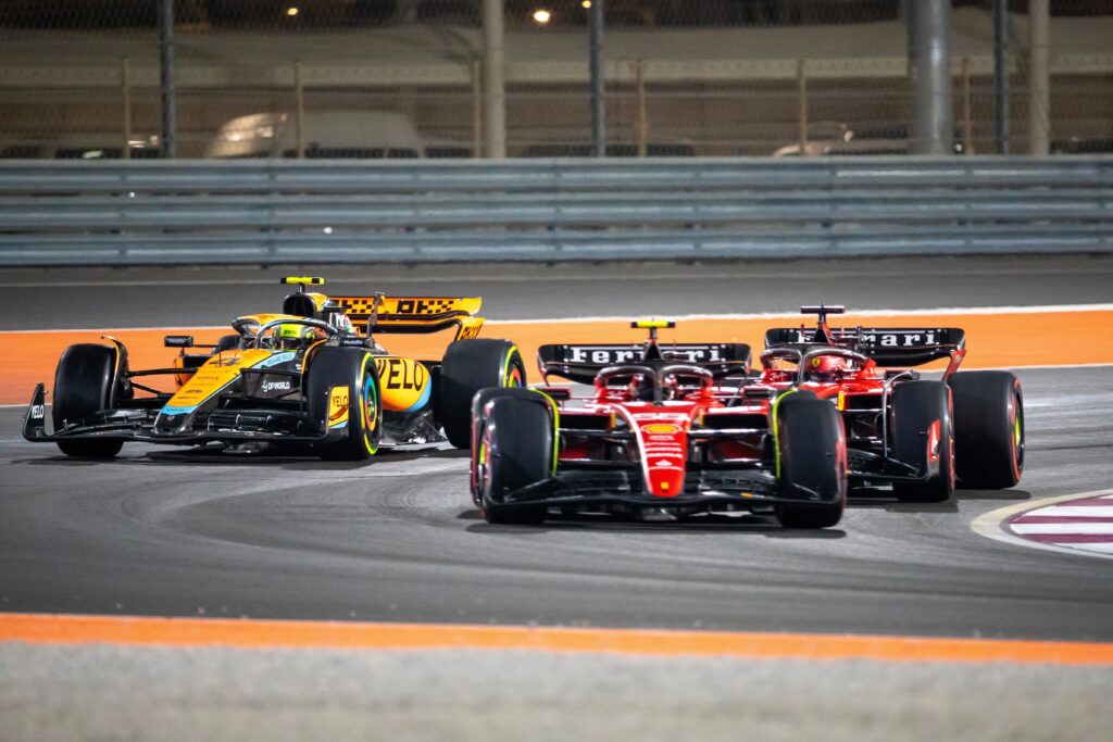 Ferrari and McLaren Formula 1 cars battling through a corner at the Qatar Grand Prix.