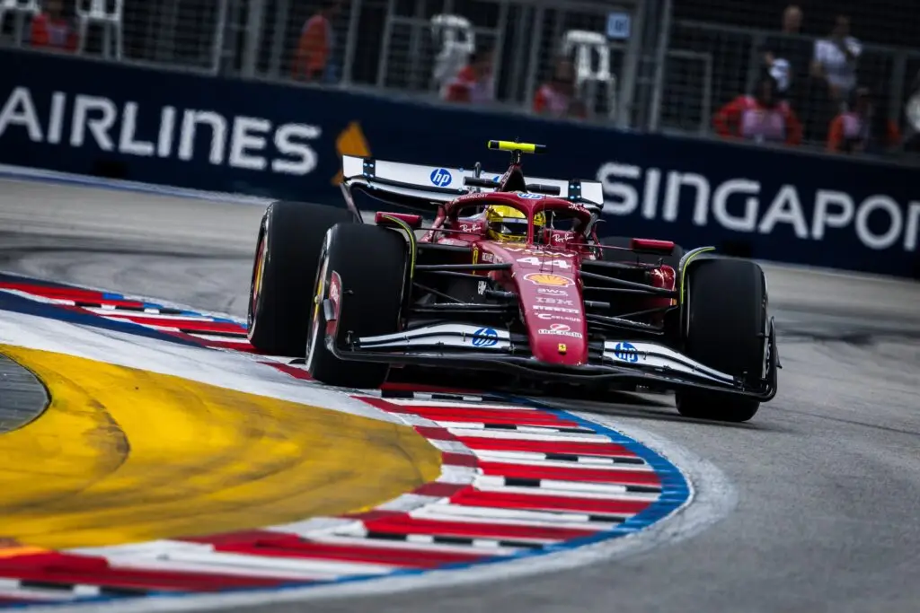 Ferrari Formula 1 car crossing the red and white kerbs at Marina Bay Street Circuit.