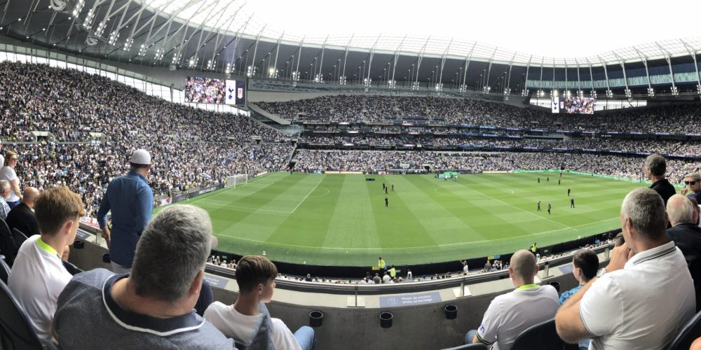 Packed stands at Tottenham Hotspur Stadium with supporters cheering during a Premier League match.